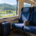 ที่นั่งรถไฟระหว่างเมืองข้างหน้าต่างในแสงกลางวันกับกระเป๋าเดินทางใบเล็ก