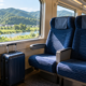 ที่นั่งรถไฟระหว่างเมืองข้างหน้าต่างในแสงกลางวันกับกระเป๋าเดินทางใบเล็ก