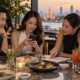 ผู้ใหญ่สี่คนกำลังตรวจรายละเอียดการจองและรายชื่อบนโต๊ะอาหารในร้าน