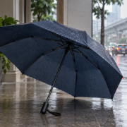 ร่มพับสีน้ำเงินเปิดบนระเบียงริมถนนฝนตก ภาพประกอบ